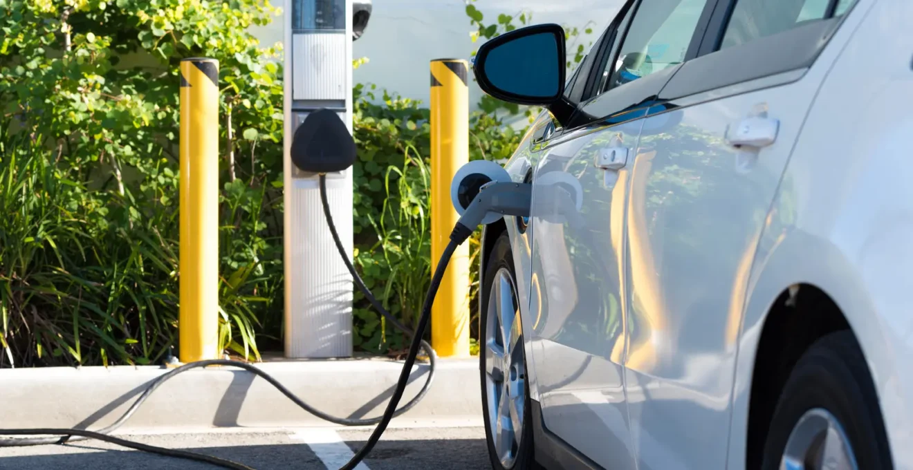 Personne branchant le câble de recharge sur son véhicule électrique à une borne domestique installée à son domicile